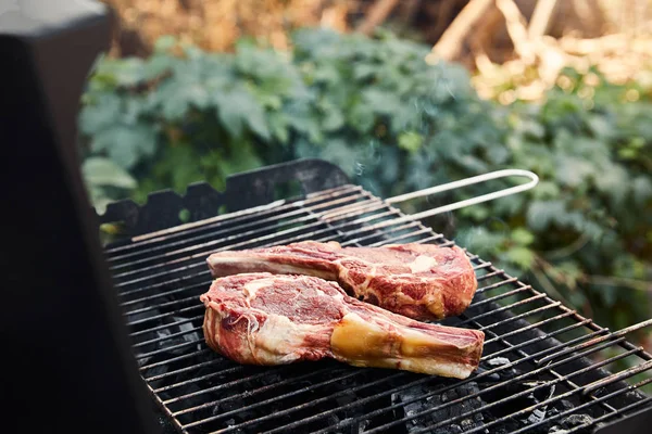 Selective focus of raw meat grilling on barbecue grid outside — Stock Photo