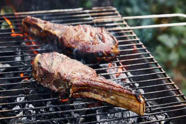 Tasty meat grilling on barbecue grid and coal pieces outside — Stock Photo