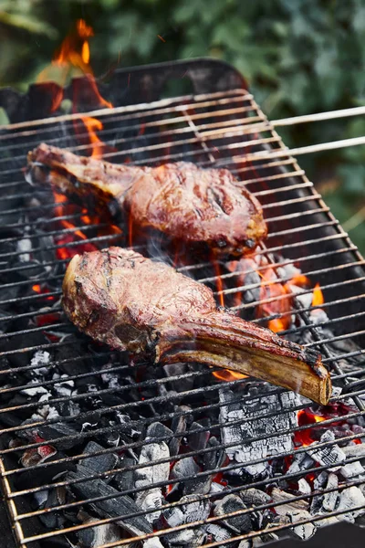 Grillade de viande savoureuse sur grille de barbecue et morceaux de charbon à l'extérieur — Photo de stock