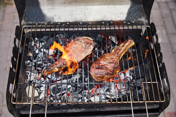 Top view of meat grilling on barbecue grid and coal pieces outside — Stock Photo