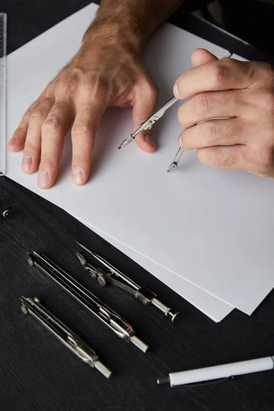 Cropped view of architect drawing with compass on white paper — Stock Photo