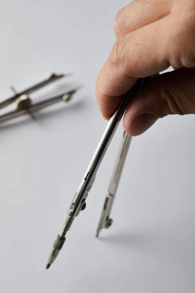 Cropped view of man drawing with compass on white paper — Stock Photo