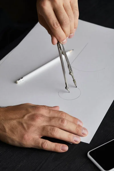 Vista ritagliata dell'uomo disegno cerchio su carta con bussola — Foto stock