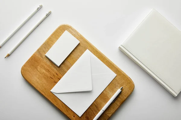 Top view of envelope, business card and pen on wooden board, notebook, pencils — Stock Photo