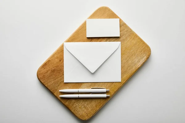 Top view of envelope, business card and pens on wooden board — Stock Photo