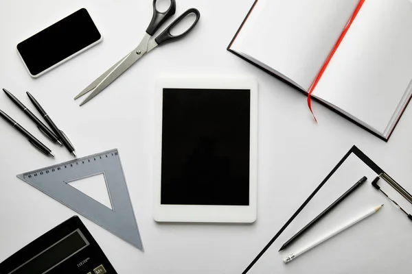 Top view of clipboard, notebook, pens, pencils, scissors, triangle ruler, calculator, smartphone and digital tablet — Stock Photo