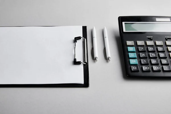 Буфер обмена с копировальным пространством, ручками и калькулятором на столе — стоковое фото