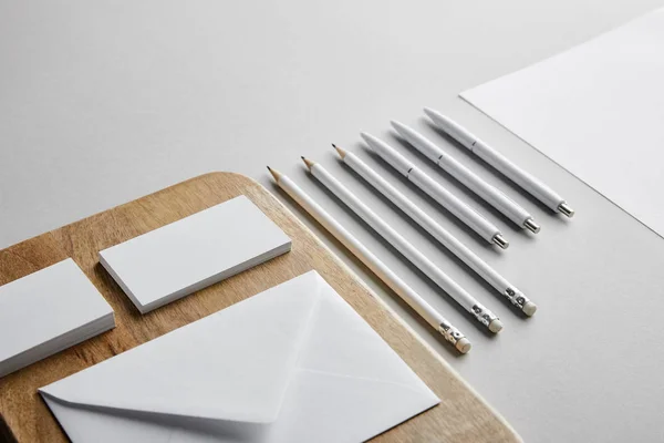 Визитные карточки и конверт на деревянной доске, ручки, карандаши, бумага — стоковое фото