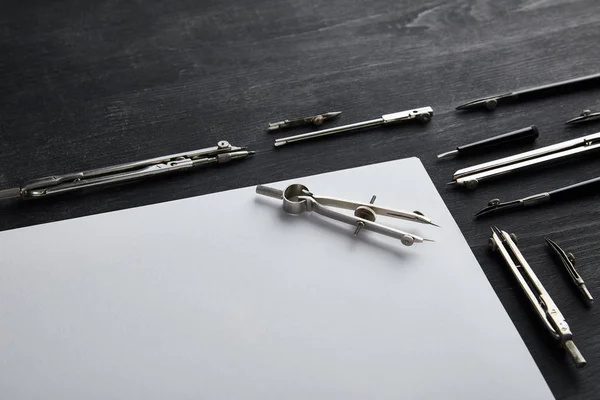 White paper with copy space and compasses on black and wooden table — Stock Photo