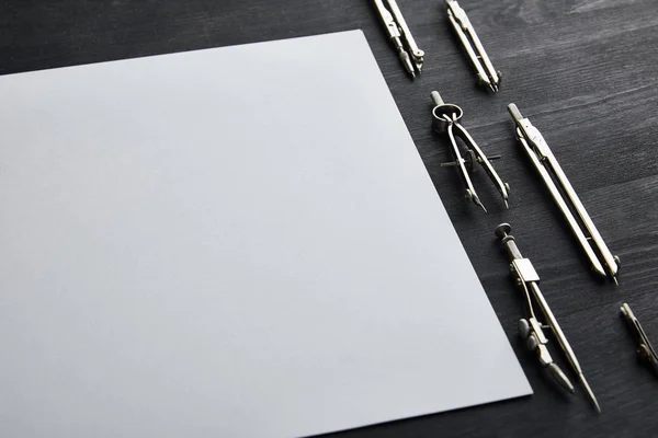 White paper with copy space and compasses on black and wooden table — Stock Photo