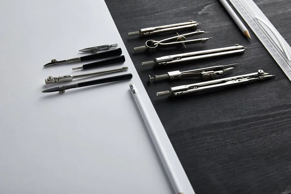 Papel blanco con espacio de copia y brújulas, regla, lápices sobre mesa de madera y negro - foto de stock