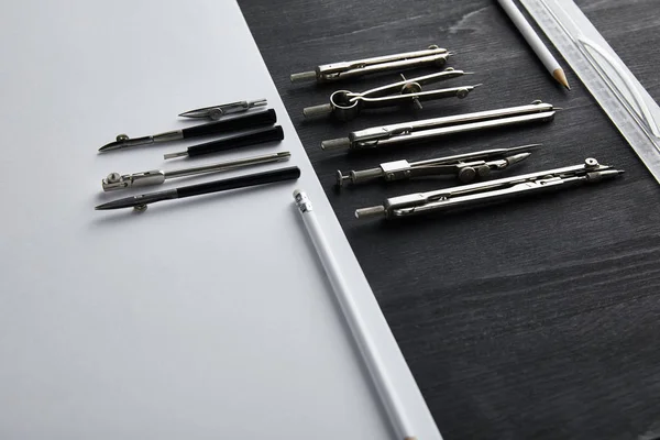 White paper with copy space and compasses, ruler, pencils on black and wooden table — Stock Photo