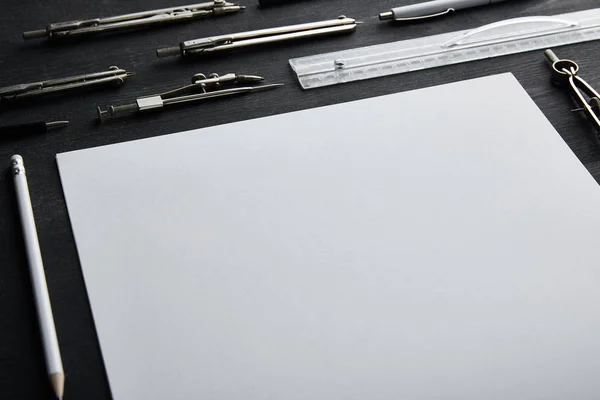 Papel blanco con espacio de copia y brújulas, regla, lápiz, pluma en la mesa de madera y negro - foto de stock