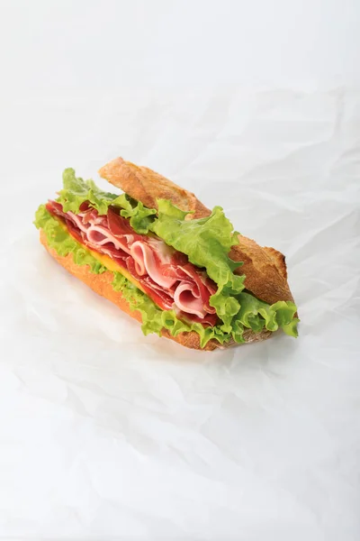 Fresh sandwich with lettuce, ham, cheese, bacon and tomato on textured white background — Stock Photo