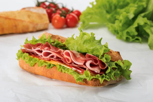 Selective focus of fresh sandwich with lettuce, ham, cheese, bacon and tomato on textured white background — Stock Photo