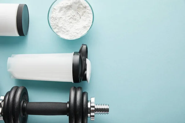 Top view of dumbbell near sports bottle and protein powder on blue — Stock Photo