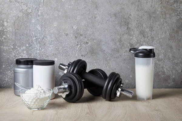 Protein shake in sports bottle near jars near concrete wall — Stock Photo