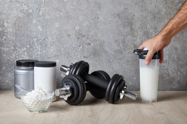 Cropped view of man holding sports bottle with protein shake near concrete wall — Stock Photo