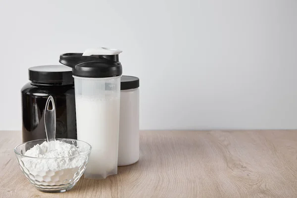 Sports bottle with protein shake near jars isolated on grey — Stock Photo