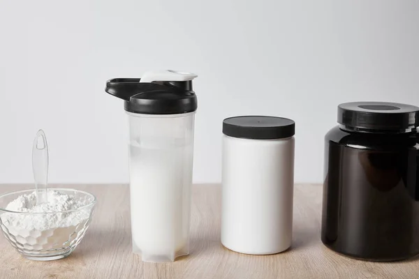 Protein shake in sports bottle near jars isolated on grey — Stock Photo