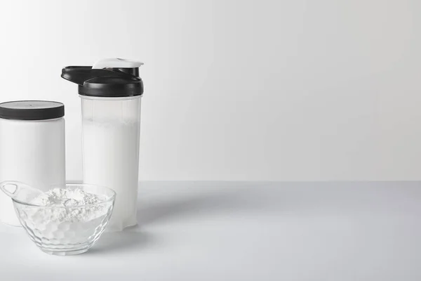 Sportflasche mit Protein-Shake in der Nähe von Glas und Protein-Pulver auf weiß — Stockfoto