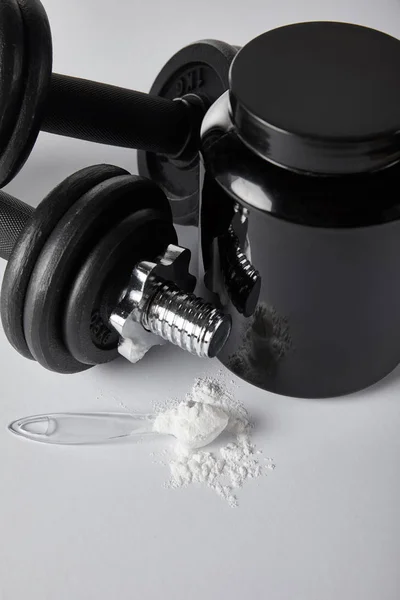 Jar near dumbbells and spoon with protein powder on white — Stock Photo