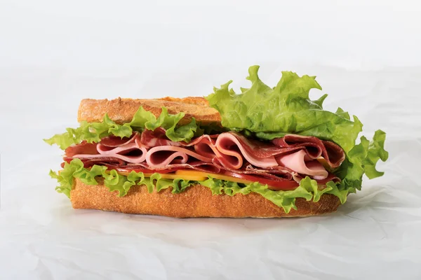 Fresh sandwich with lettuce, ham, cheese, bacon and tomato on textured white background — Stock Photo