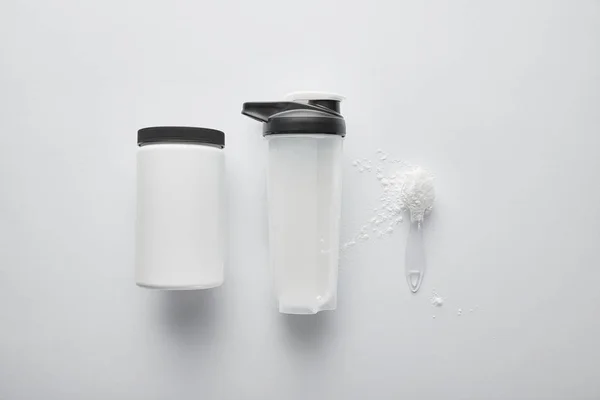 Top view of jar near spoon with protein and sports bottle on white — Stock Photo