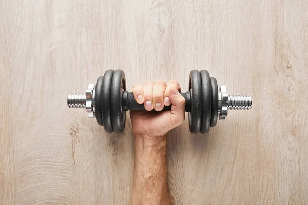 Vue de dessus du sportif tenant un haltère près de la surface en bois — Photo de stock