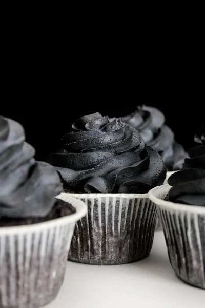 Delicious Halloween cupcakes with black cream isolated on black — Stock Photo