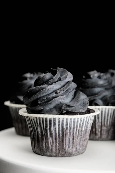 Deliciosos cupcakes de Halloween con crema negra aislada en negro - foto de stock