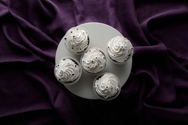 Top view of delicious Halloween cupcakes with white cream on stand on purple cloth — Stock Photo