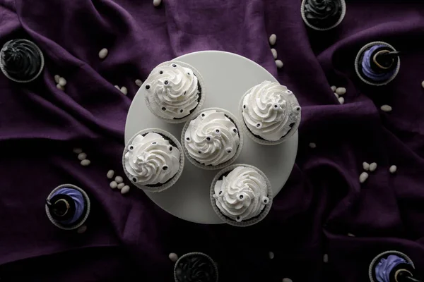 Top view of delicious Halloween cupcakes on stand and on purple cloth — Stock Photo