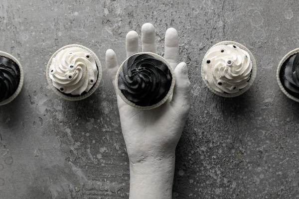 Top view of delicious Halloween cupcake in decorative hand on concrete grey surface — Stock Photo