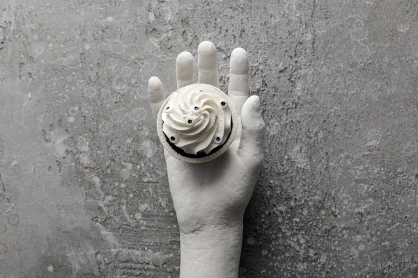 Верхний вид вкусный кекс Хэллоуин в декоративной руке на бетонно-серой поверхности — стоковое фото