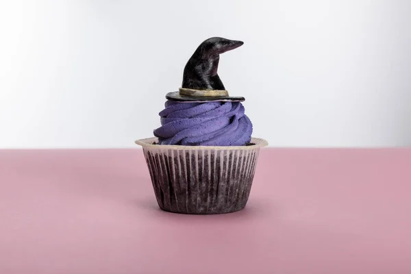 Delicious Halloween cupcake with purple cream and hat on pink surface isolated on white — Stock Photo