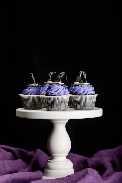 Tasty Halloween cupcakes on white stand on purple cloth isolated on black — Stock Photo