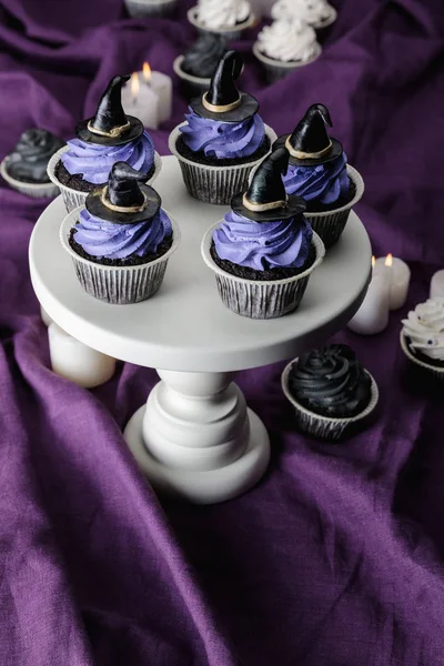 Sabrosos cupcakes de Halloween en blanco stand púrpura tela - foto de stock