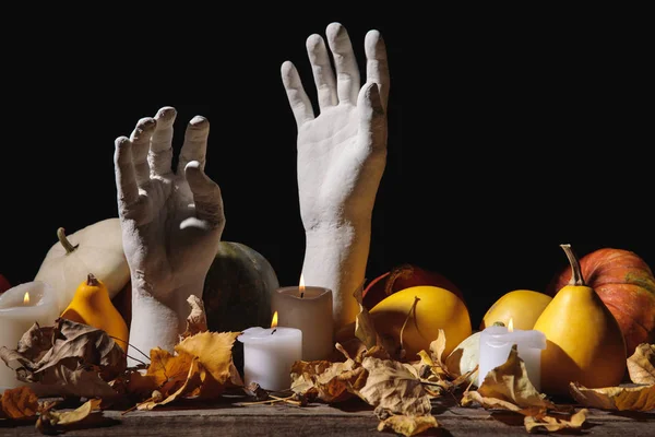 Dry foliage, burning candles, ripe pumpkin and decorative hands on wooden rustic table isolated on black — Stock Photo