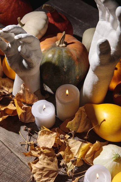 Folhagem seca, velas em chamas, abóbora madura e mãos decorativas sobre mesa rústica de madeira — Fotografia de Stock