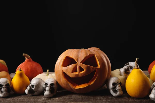 Calabazas de Halloween y calaveras decorativas sobre mesa rústica de madera aislada en negro - foto de stock