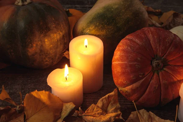 Сухе листя, палаючі свічки, стиглий гарбуз на дерев'яному сільському столі — стокове фото