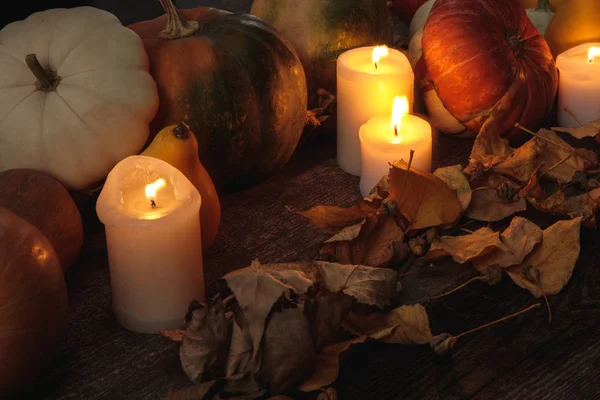 Fogliame secco, candele accese, zucca matura su tavolo rustico in legno — Foto stock