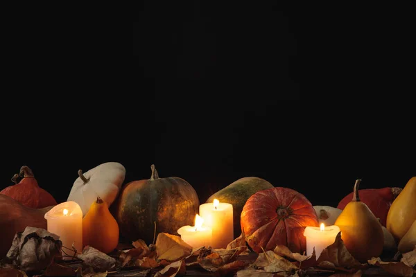 Dry foliage, burning candles, ripe pumpkin on wooden rustic table isolated on black — Stock Photo