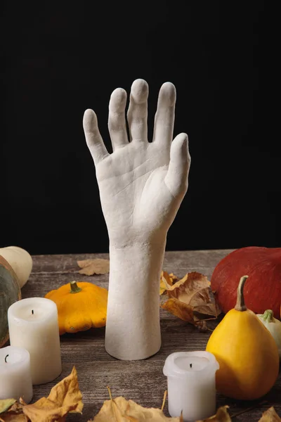 Dry foliage, candles, ripe pumpkins and decorative hand on wooden rustic table isolated on black — Stock Photo