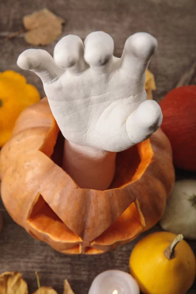 Top view of decorative hand in carved Halloween pumpkin on wooden rustic table — Stock Photo