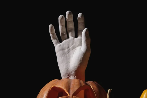 Dekorative Hand in geschnitztem Halloween-Kürbis isoliert auf schwarz — Stockfoto