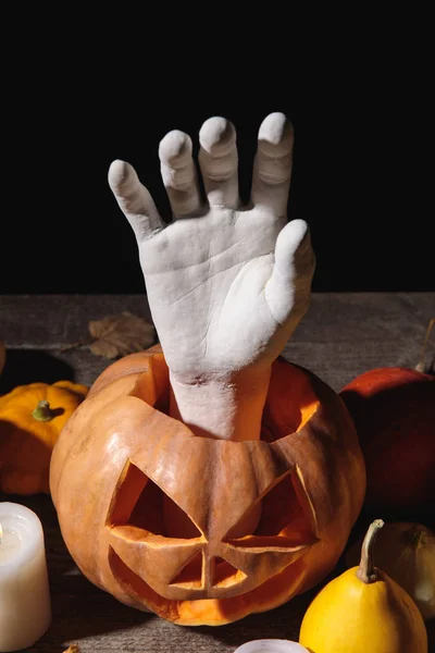 Trockenes Laub, Kerzen, dekorative Hand in geschnitztem Halloween-Kürbis auf rustikalem Holztisch isoliert auf schwarz — Stockfoto