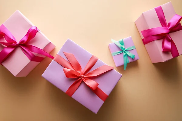 Top view of colorful gift boxes with ribbons on beige background — Stock Photo