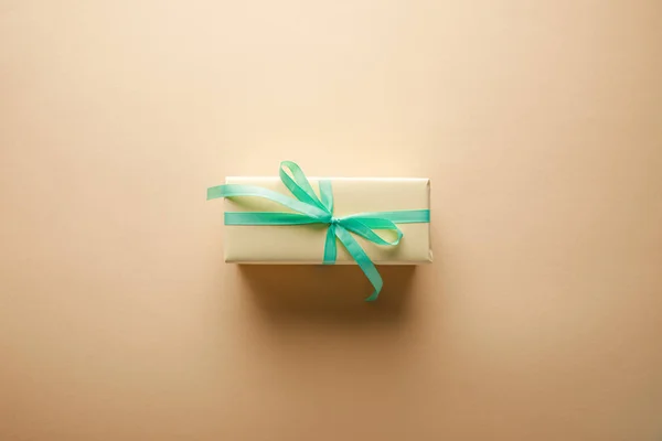 Top view of gift box with green ribbon on beige background — Stock Photo